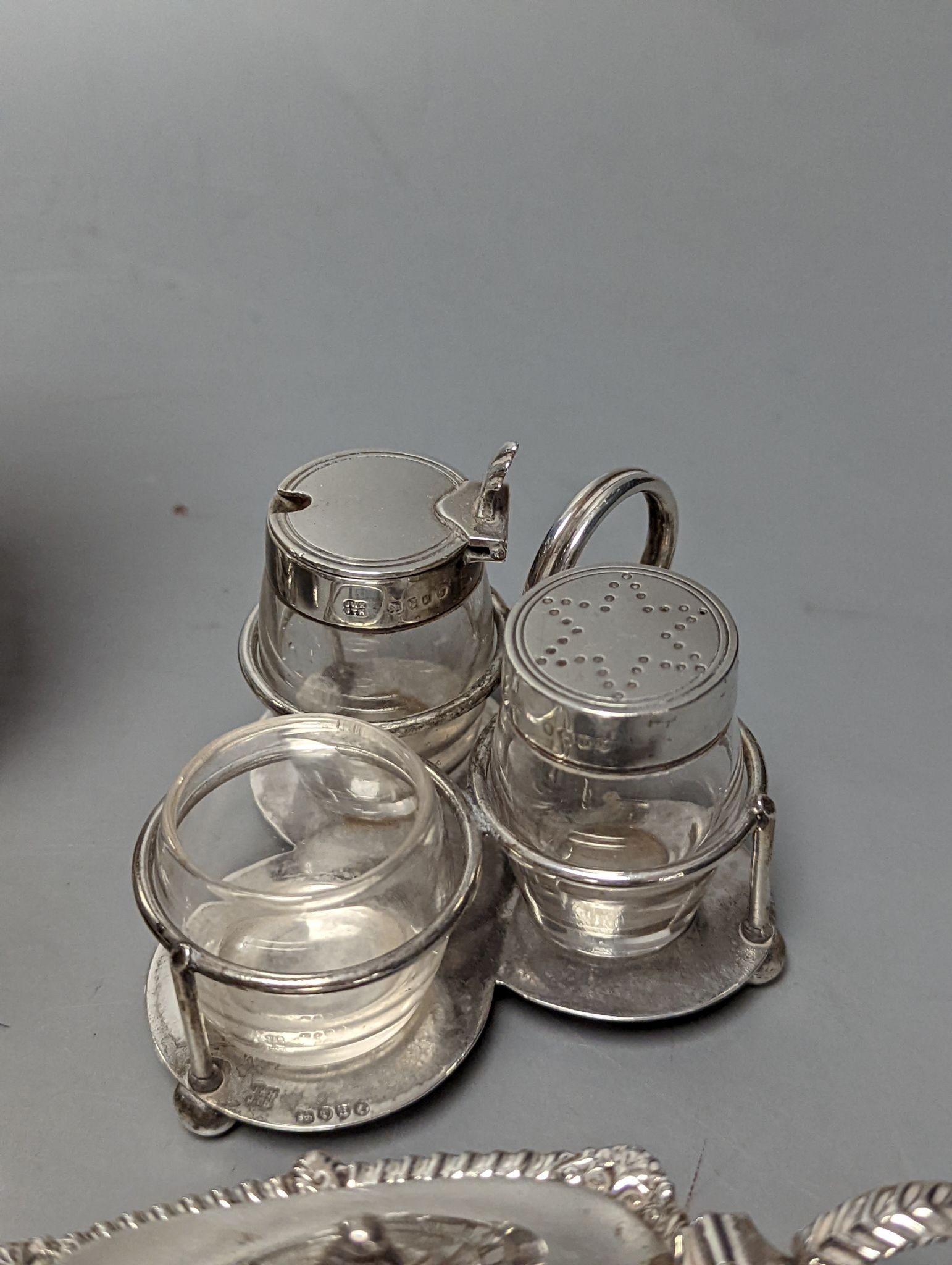 A late Victorian small silver condiment stand with three glass condiments, London, 1883, 49mm, other minor condiments and a silver sugar caster.